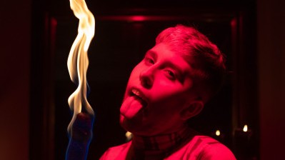 An image of instructor Jamie Joy with their mouth open while holding a lit torch.