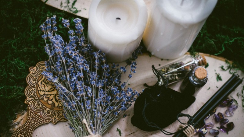 Image of an altar with candles and herbs on a stone.