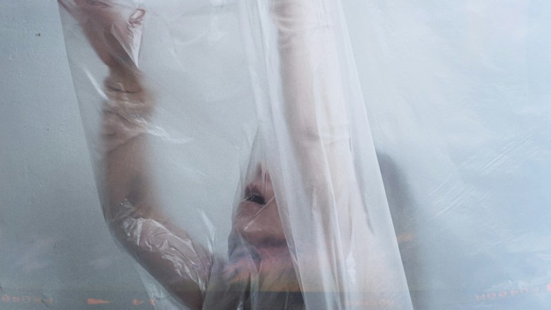 Woman behind a transparent shower curtain looking afraid but ecstatic.