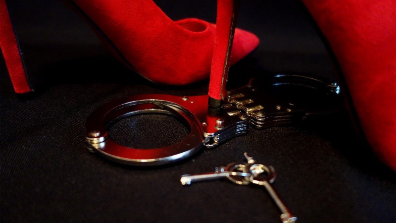 An image of handcuffs against a red background.