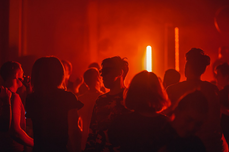 A dimly lit party scene with a red overglow.