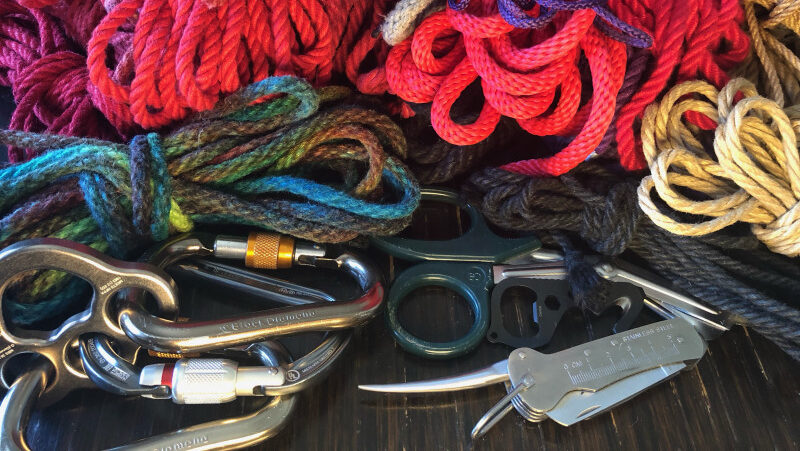 A colorful bundle of rope with carabiners, safety shears, and a marlin spike.